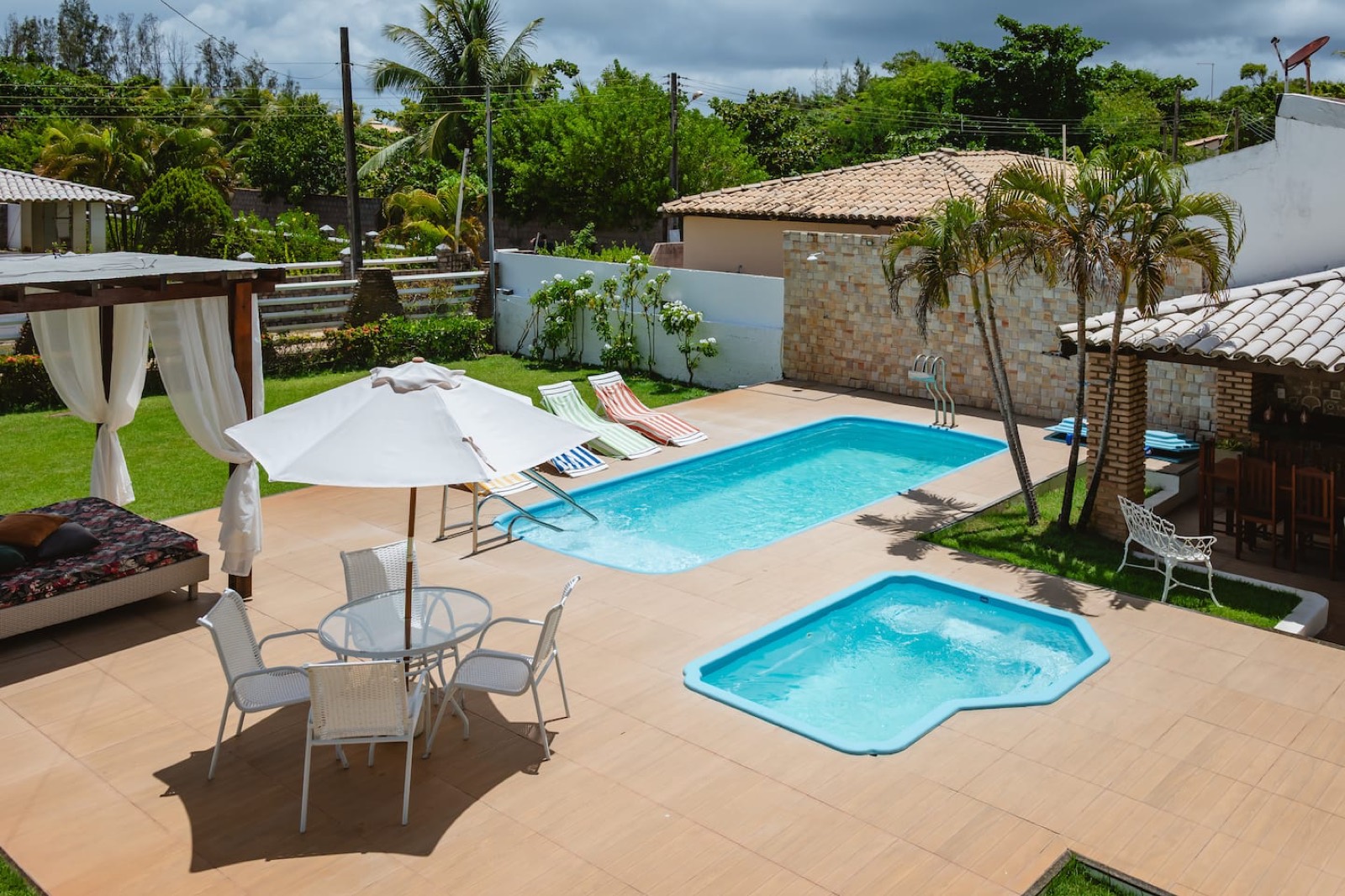Área de piscina com gazebo e palmeiras